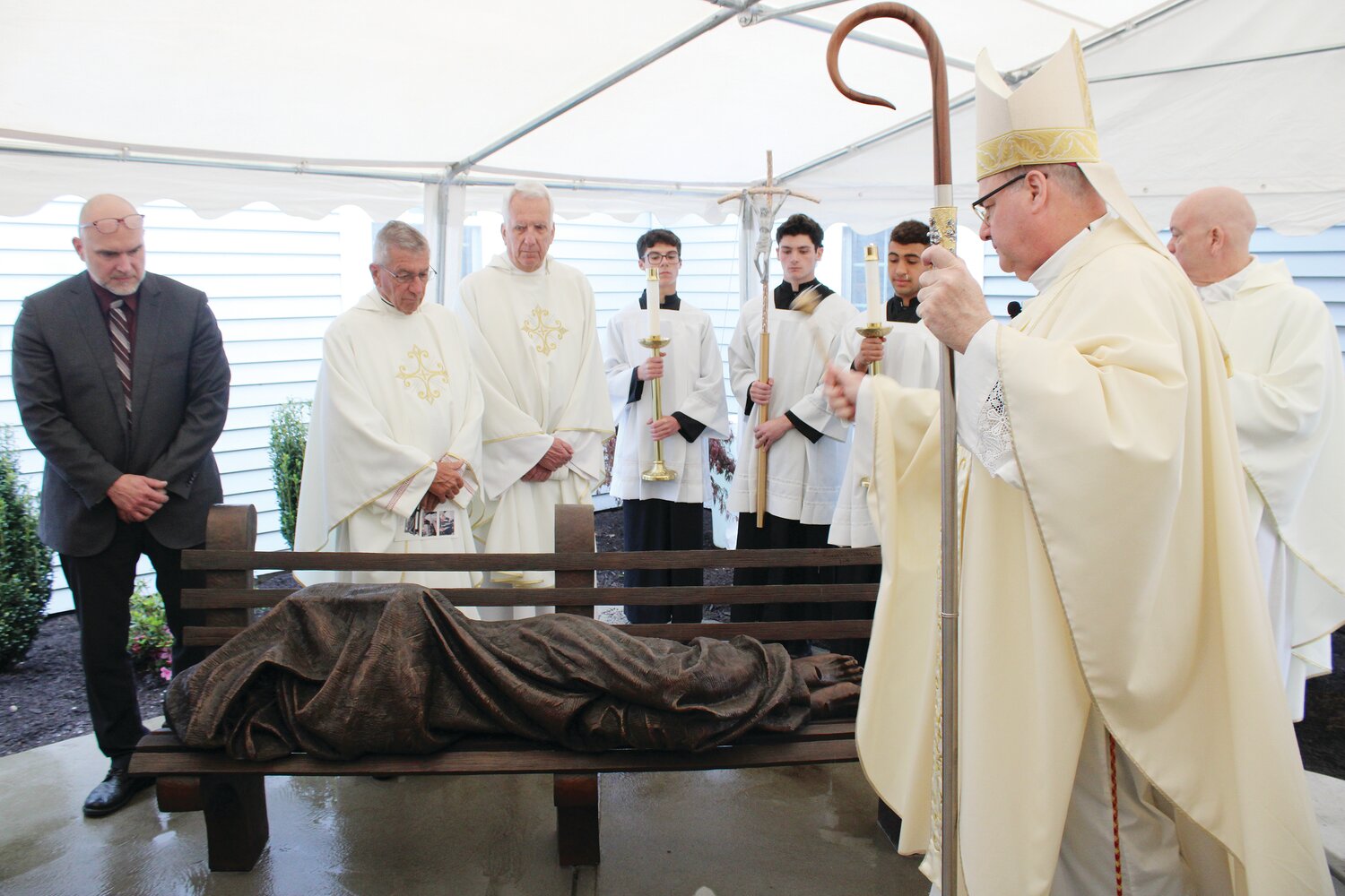 Bishop Richard G. Henning visits Holy Apostles Church in Cranston to celebrate Mass and to bless the new “Homeless Jesus” sculpture by Timothy Schmalz, at left. Inspired by Matthew 25, the sculpture suggests Christ is with the most marginalized in society. The figure is shrouded in a blanket with the only indication that it is Jesus being the visible wounds on the feet.